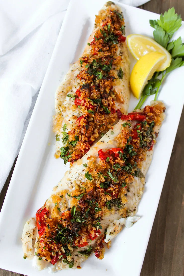 Greek white fish on serving platter with lemon wedge.