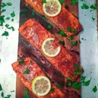 Finished cedar planked salmon garnished with lemon slices and chopped parsley.