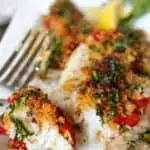 Greek white fish on plate with portion flaked with fork.