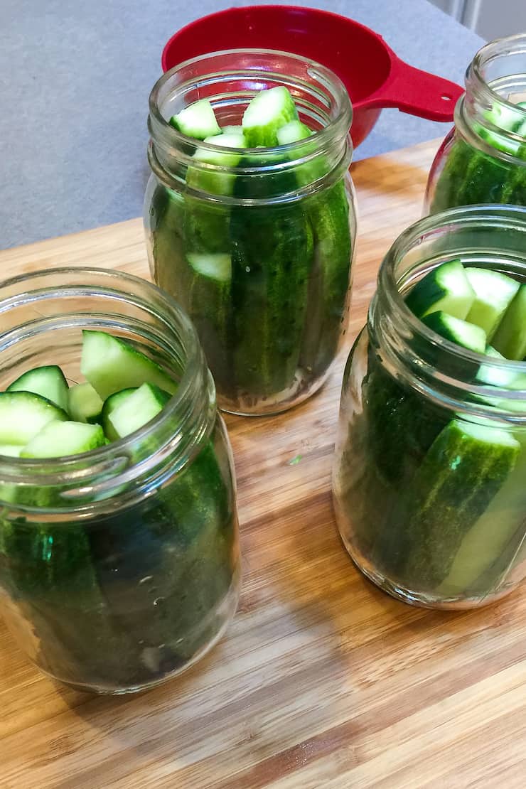Filling sterilized jars with cucumber spears.