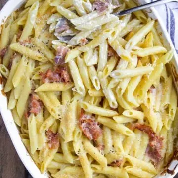 Baked penne with prosciutto and Parmesan cream in casserole dish.