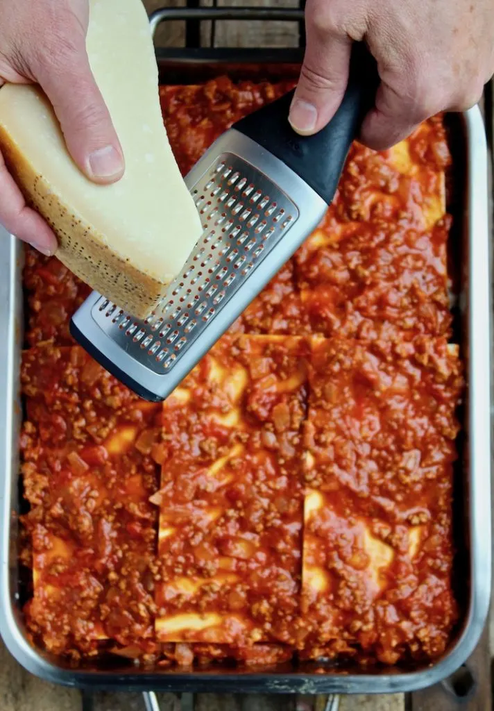 Grating Parmesan over top of lasagna before baking