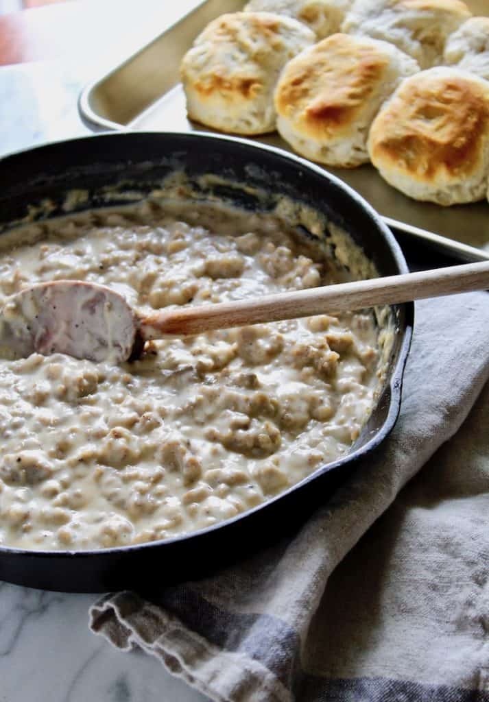 Sausage Gravy and Biscuits, gravy in skillet with biscuits in background.