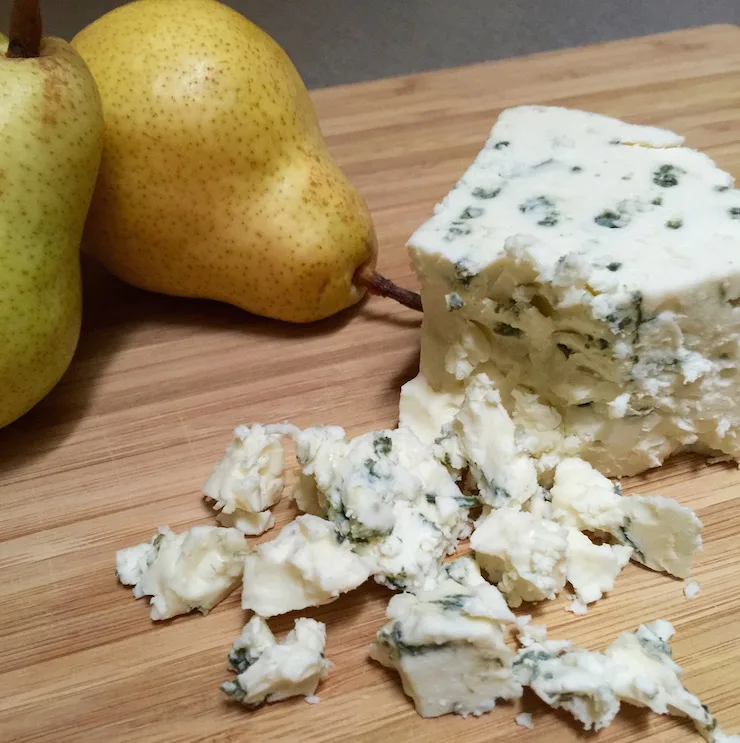 Crumbled blue cheese on cutting board.