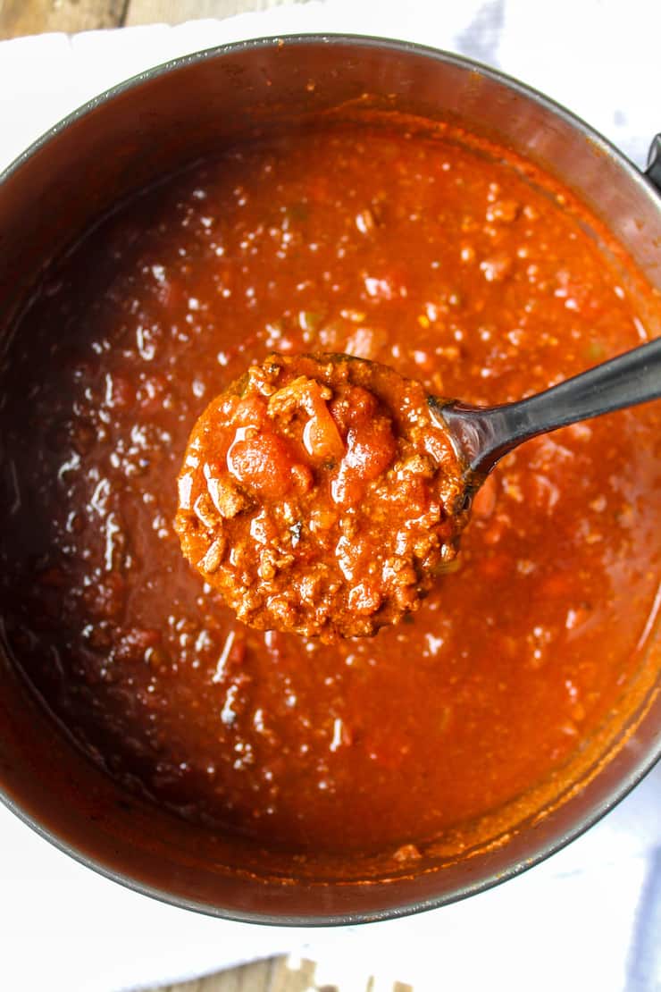 Spoonful of chili above pot.