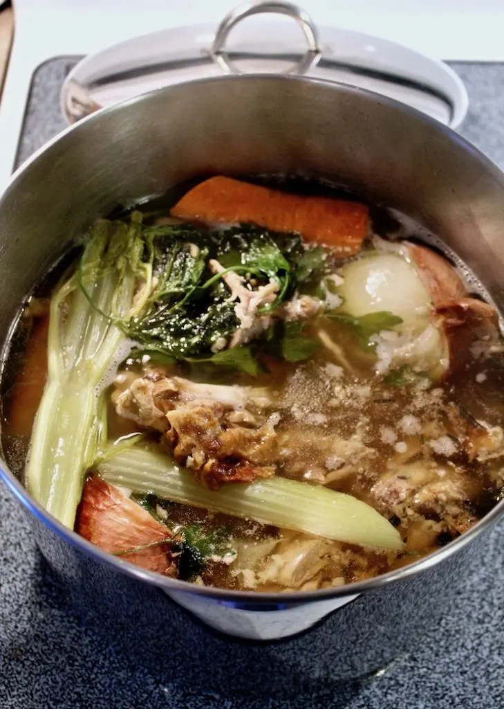 Carcass and vegetable ingredients in pot to simmer for broth.
