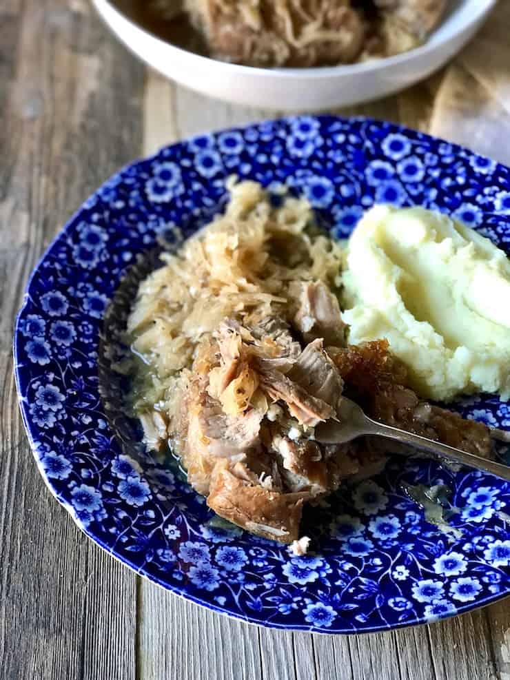 Pork and sauerkraut on plate with fork and mashed potatoes