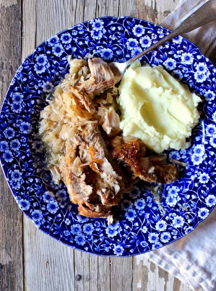 Braised Pork and Sauerkraut, on blue serving plate with forkful of pork, mashed potatoes