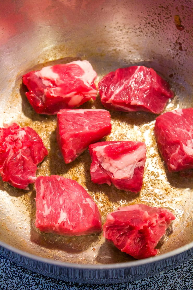 Beef chuck pieces browning in bacon fat.