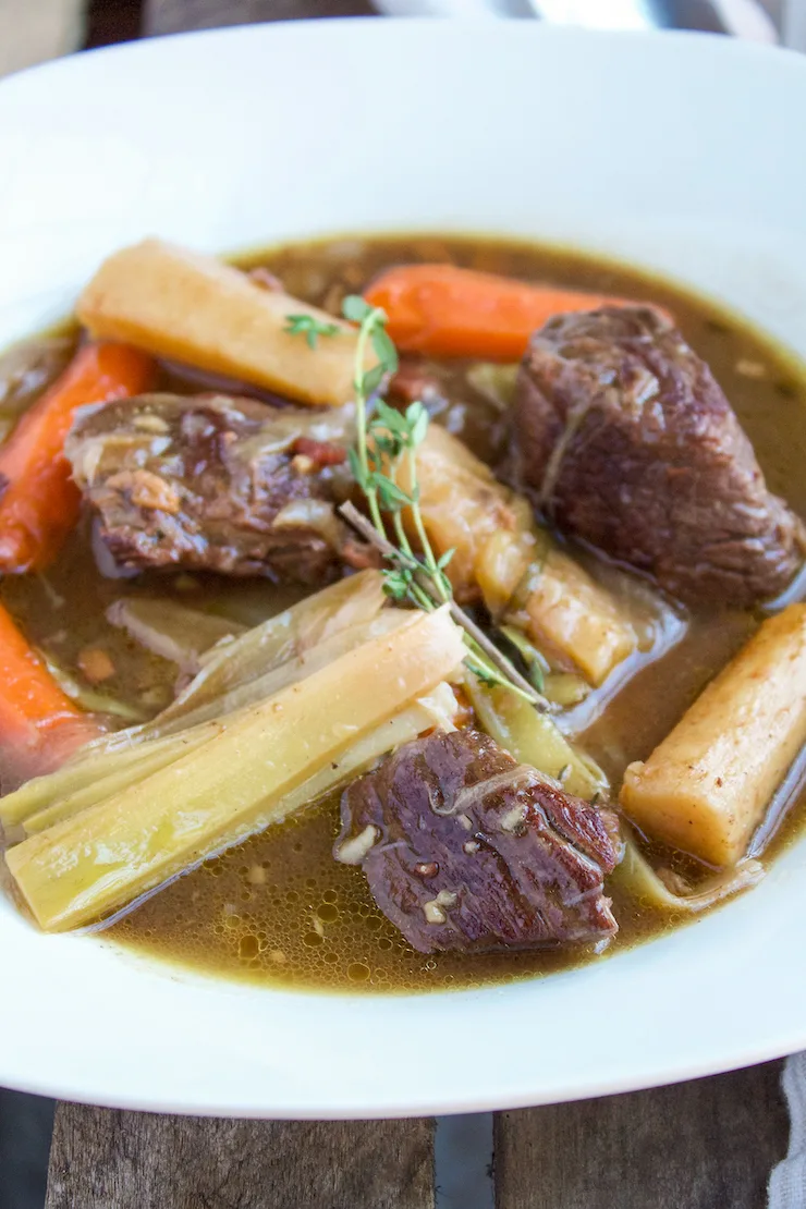 Close up of stew plated and garnished with thyme sprig.