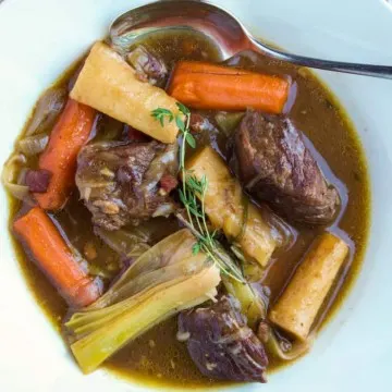 Beef stew in serving bowl with spoon.