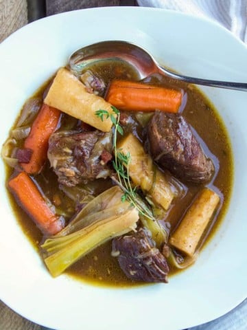 Beef stew in serving bowl with spoon.