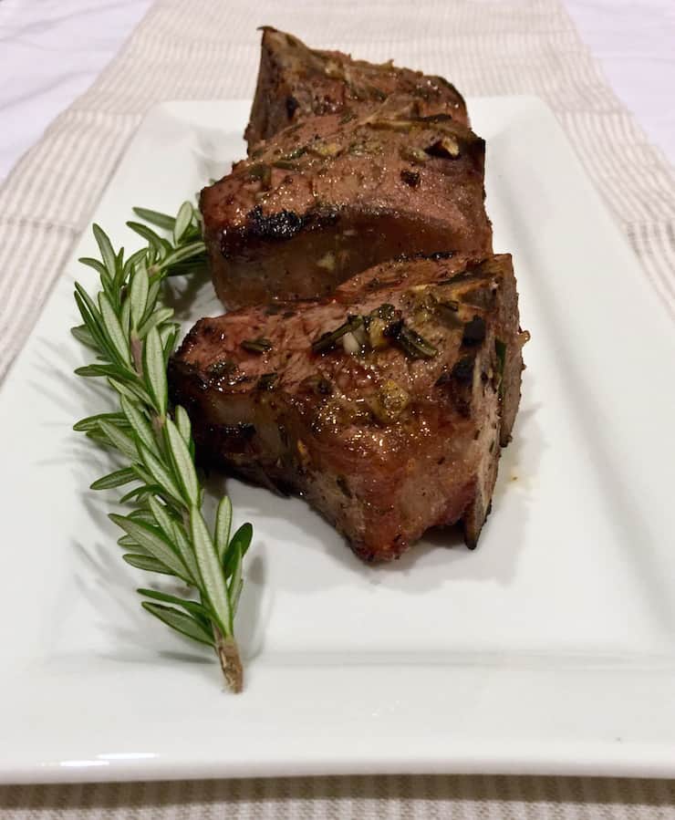 Grilled chops on platter with sprig of rosemary.