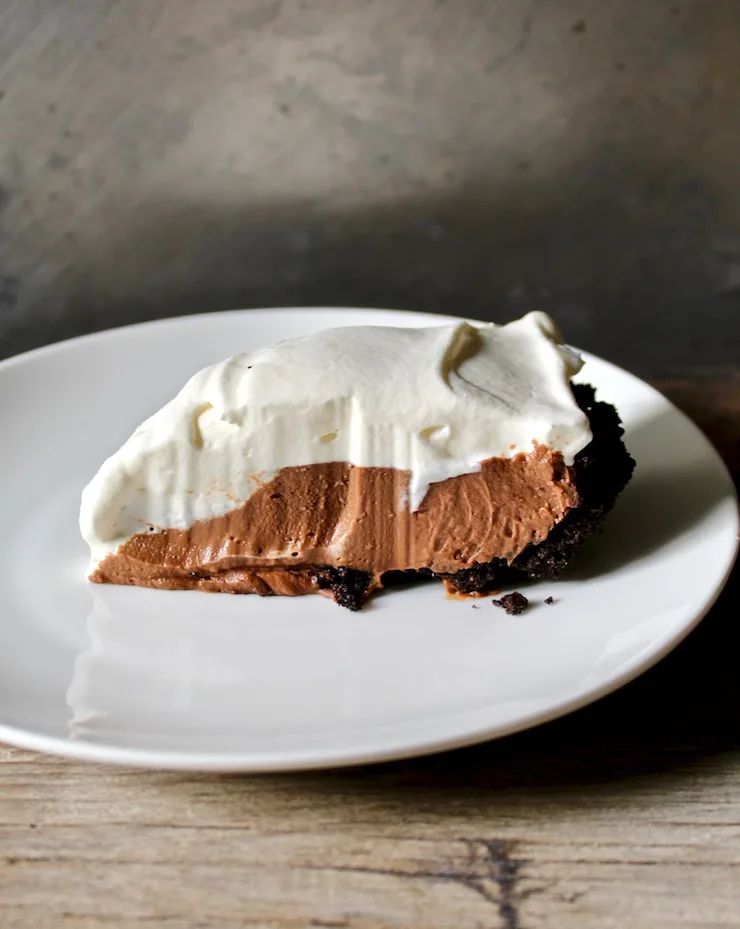 Slice of chocolate cream pie on white plate.