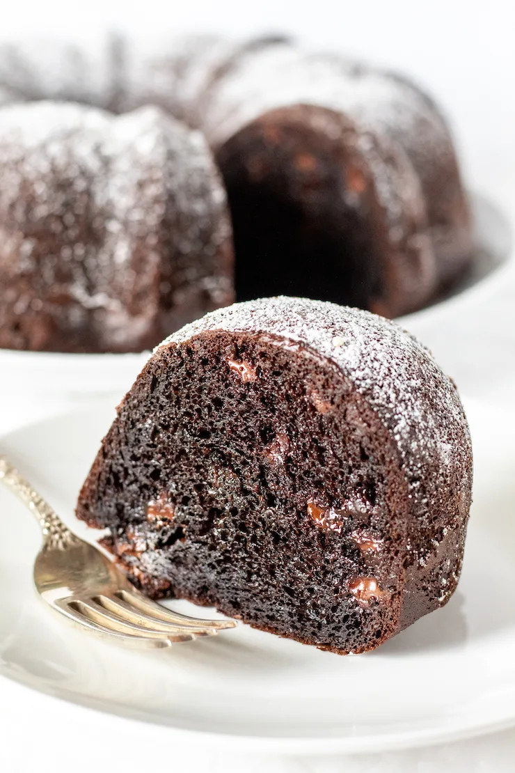 Piece of triple chocolate cake on plate with fork.