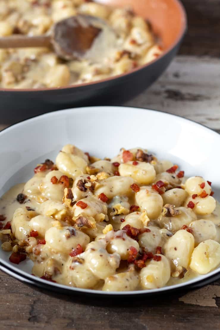 Gnocchi with gorgonzola, walnuts and pancetta on serving plate.