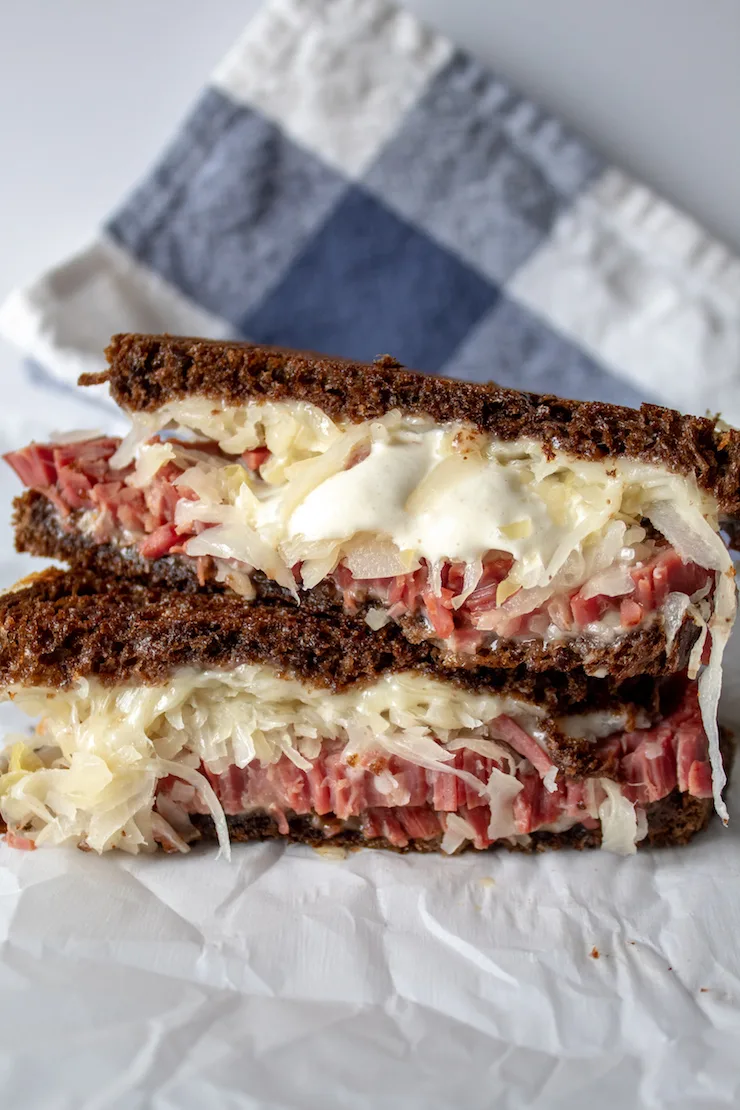 Reubens, grilled Reuben sandwich cut in half and stacked.