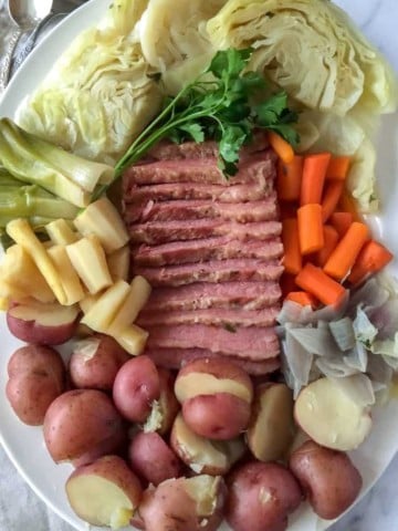 Corned Beef and Cabbage, on serving platter, sliced corned beef surrounded by cabbage and vegetables.