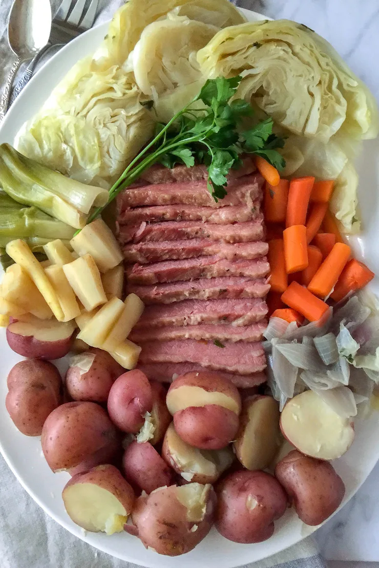 Corned Beef and Cabbage, on serving platter, sliced corned beef surrounded by cabbage and vegetables.