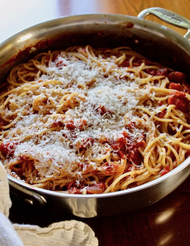 Spaghetti with Bacon Sauce, in skillet with grated cheese on top