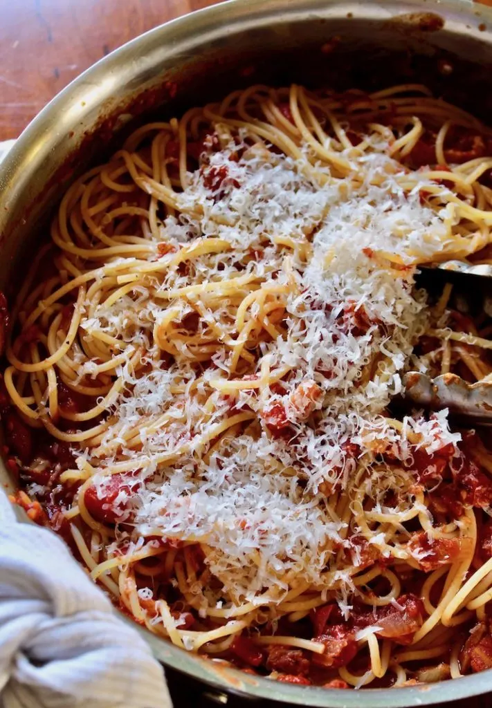 Spaghetti with Bacon Sauce, in skillet with grated cheese and tongs