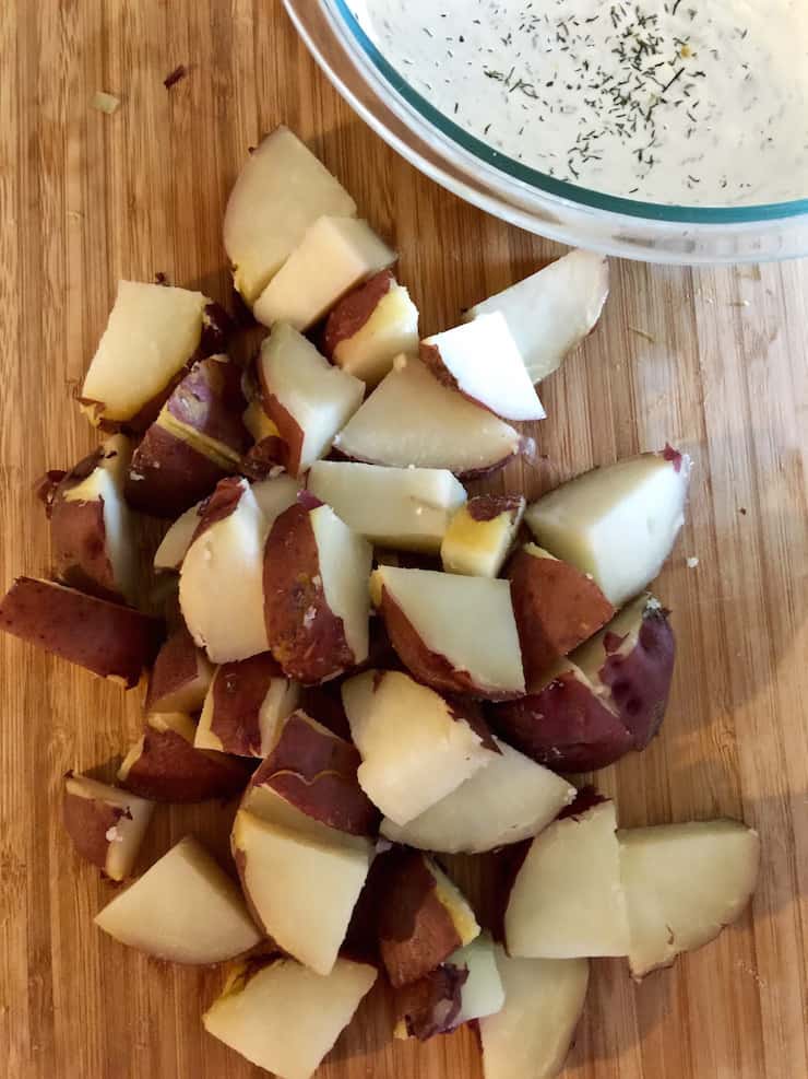 Honey's Potato Salad, cubed red potatoes on cutting board and dressing in bowl.