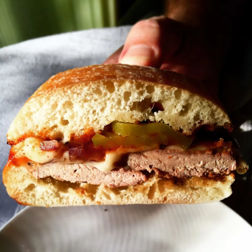 Grilled Pork Tenderloin Sandwich, holding sandwich to show filling