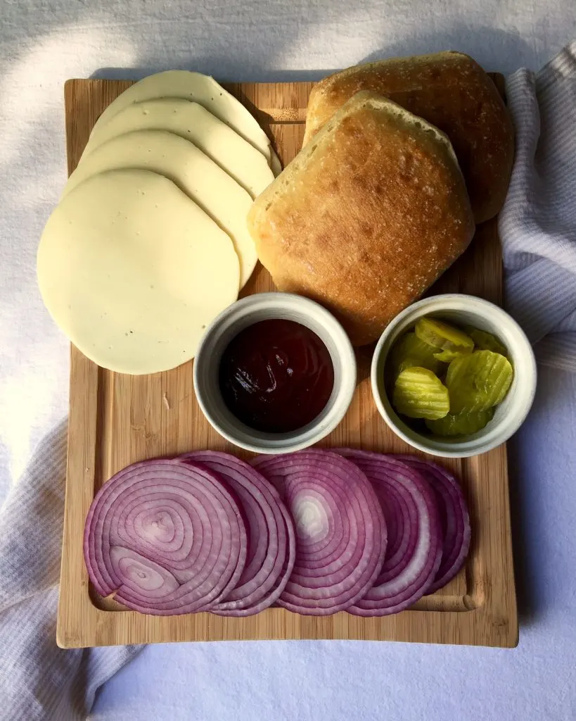 Grilled Pork Tenderloin Sandwiches, toppings and buns on cutting board