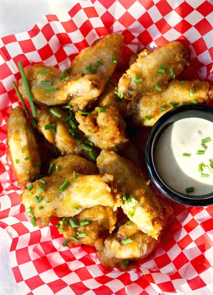 Hot Apricot Glazed Wings in basket sprinkled with snipped chives, and blue cheese dressing.