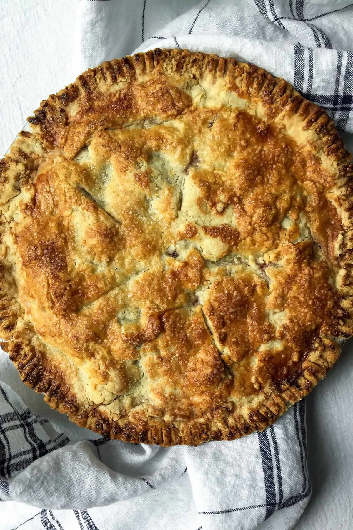 Overhead close up of baked homemade cherry pie, showing browned flaky crust.