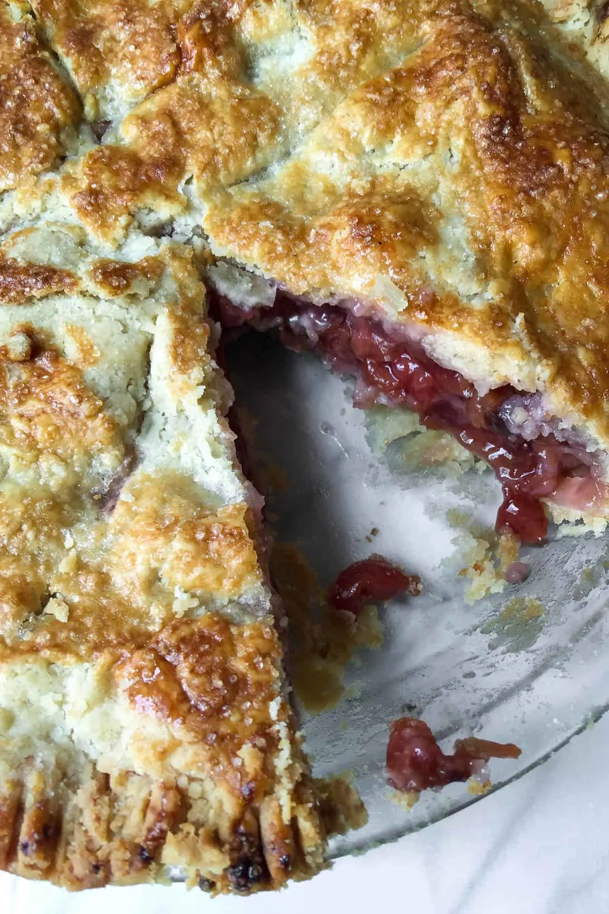 Close up of cherry pie with a piece cut out.