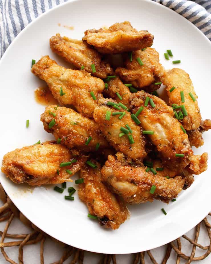 Hot Apricot Glazed Wings on white plate sprinkled with chives.