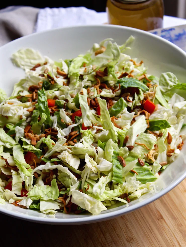 Napa Cabbage Salad, undressed in bowl, dressing and recipe in background.