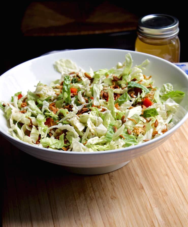 Napa Cabbage Salad, in bowl with dressing in background.