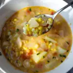 Corn chowder in serving bowl with spoonful close up