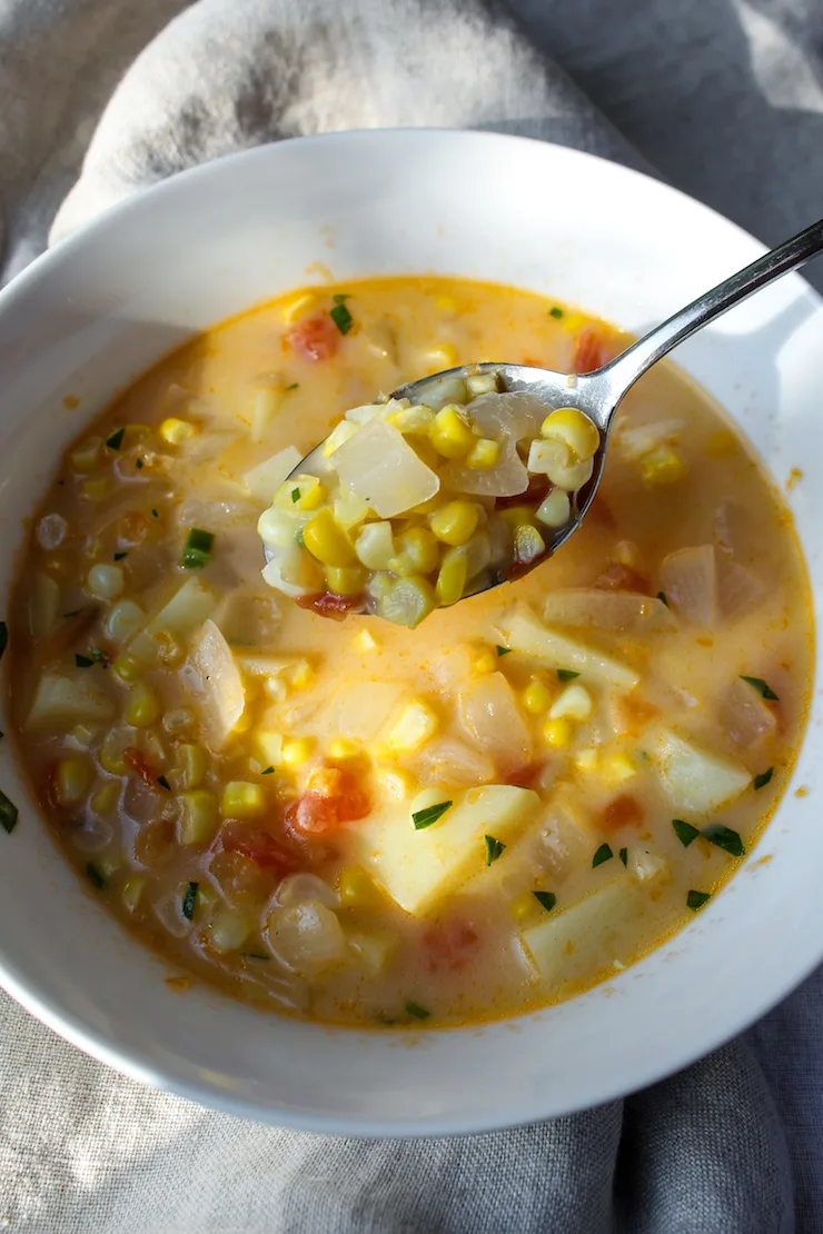 Corn chowder in serving bowl with spoonful close up