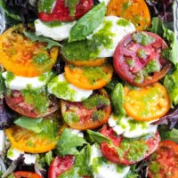 Insalata caprese with fresh mozzarella and basil dressing on serving platter.