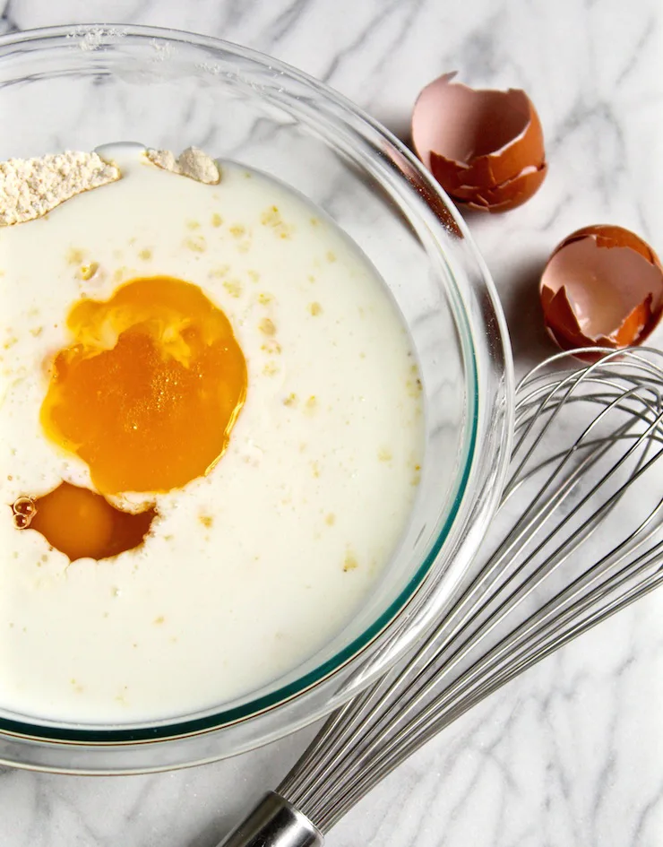 Wet ingredients on top of dry ingredients in mixing bowl with whisk.