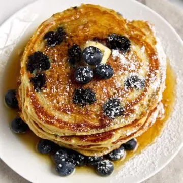 Cornmeal Blueberry Pancakes, overhead shot on plate with butter and syrup