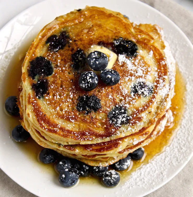Cornmeal Blueberry Pancakes, overhead shot on plate with butter and syrup.