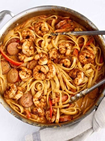 Creamy Cajun Shrimp Pasta in large skillet with tongs