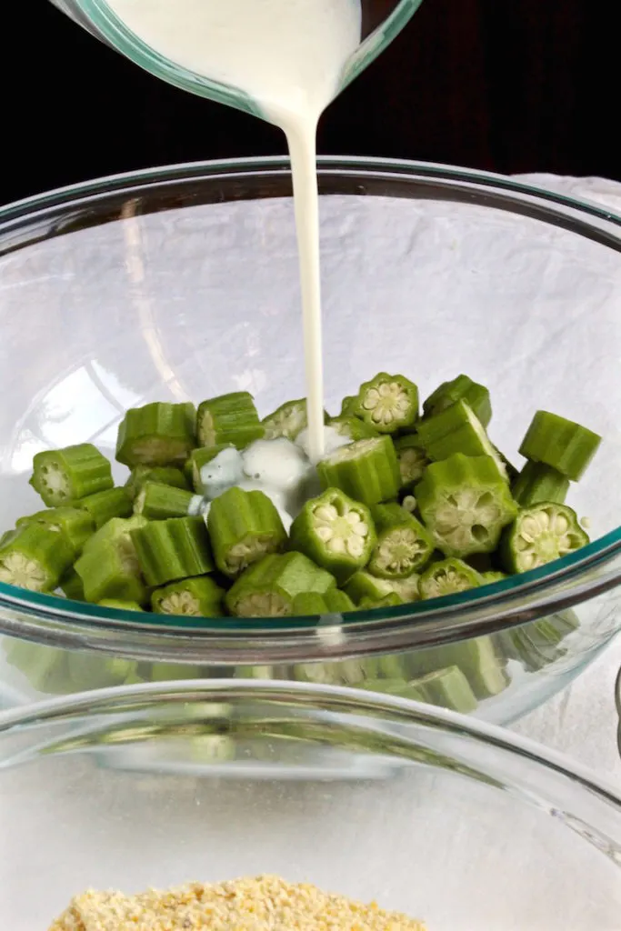 Pouring buttermilk over fresh sliced okra.