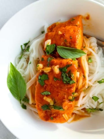 Plated coconut curry salmon over rice stick noodles.