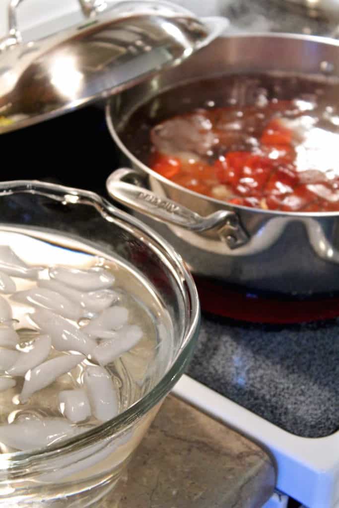 Lobster cooking in pot next to ice water bath