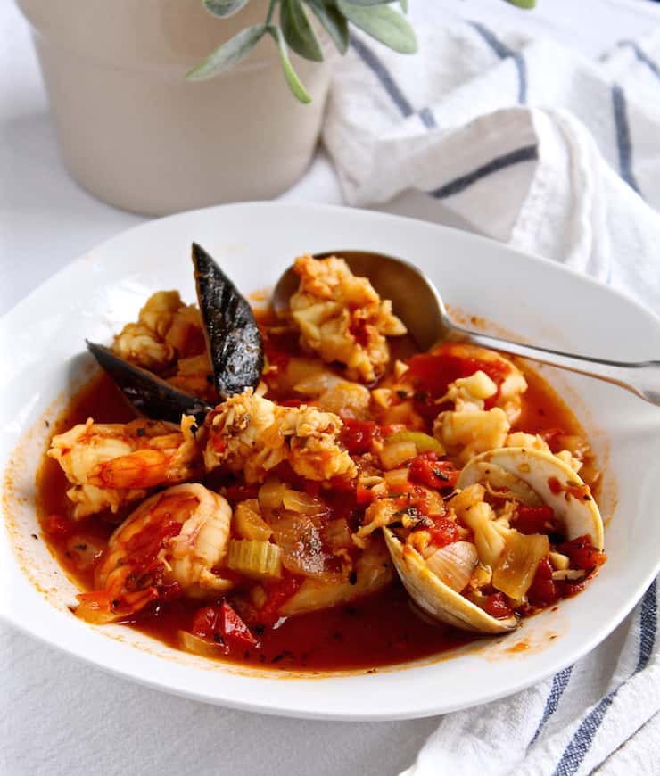 Classic Cioppino, in serving bowl with spoon showing all the seafood.