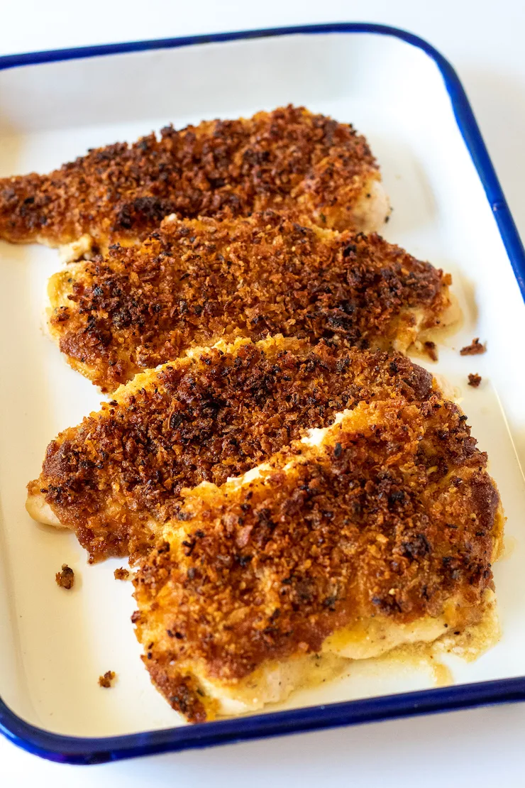 Baked chicken breasts displayed in enamelware pan.