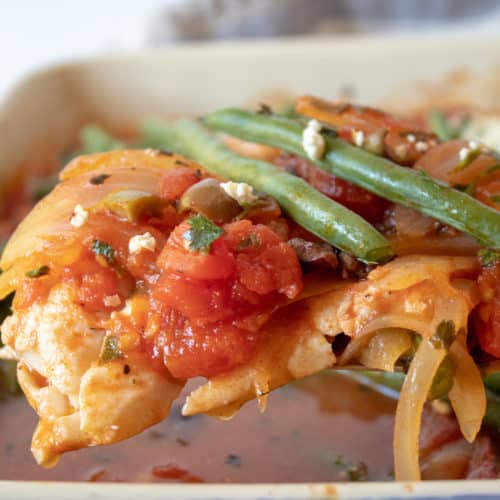 Mediterranean Baked Fish, close up on spatula with tomato mixture and green beans.