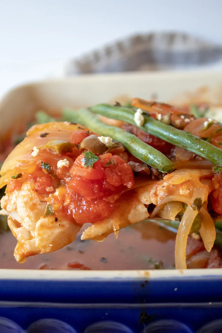 Mediterranean Baked Fish, close up on spatula with tomato mixture and green beans.