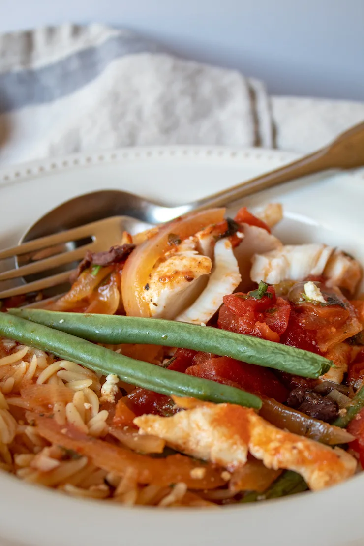 Mediterranean Baked Fish, in serving bowl with orzo pasta.