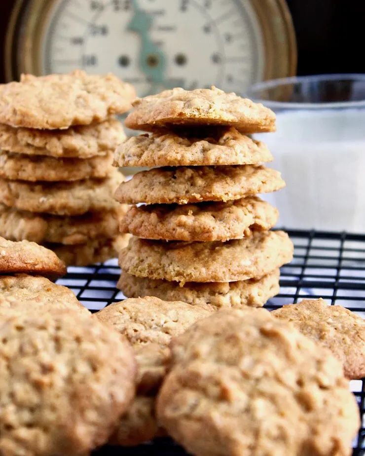 Old-Fashioned Oatmeal Cookies, stacked vertically on cooling rack with glass of milk